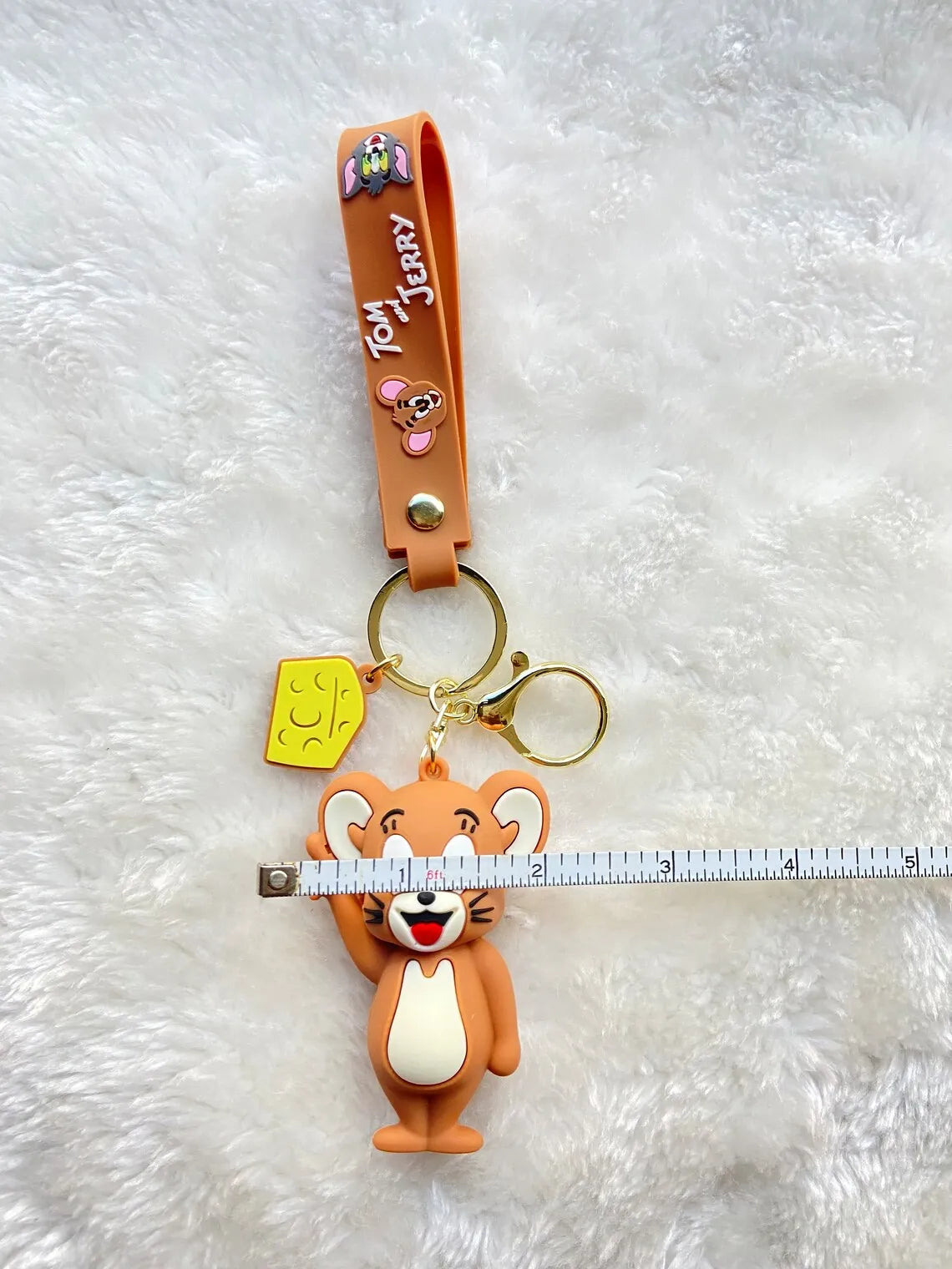 Jerry 3D rubber keychain on white fur surface with wrist strap and cheese charm