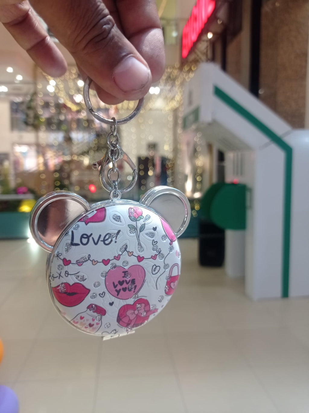 Four bear compact mirror keychains with printed designs held in hand