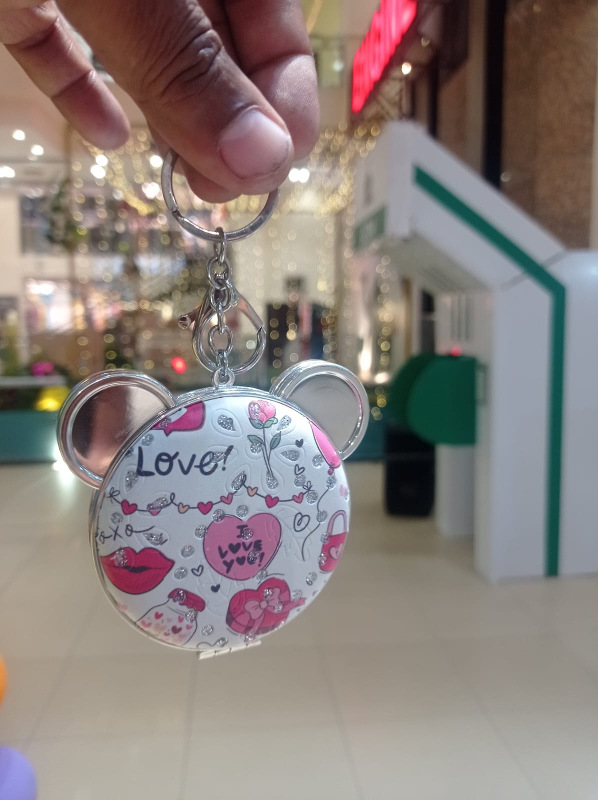 Four bear compact mirror keychains with printed designs held in hand