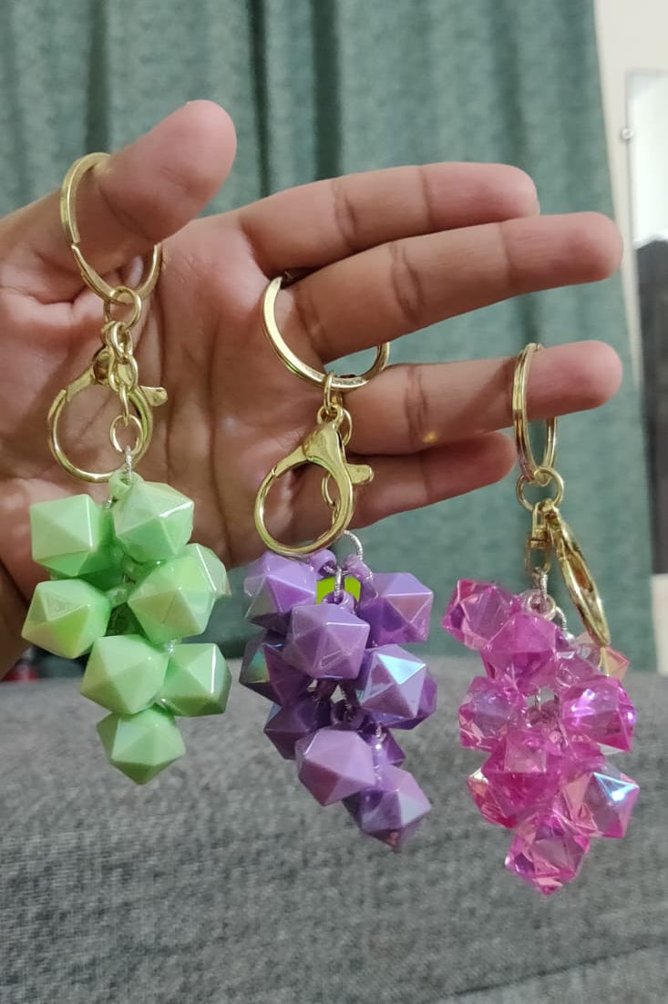 Green, purple and pink crystal grape cluster keychains held in hand