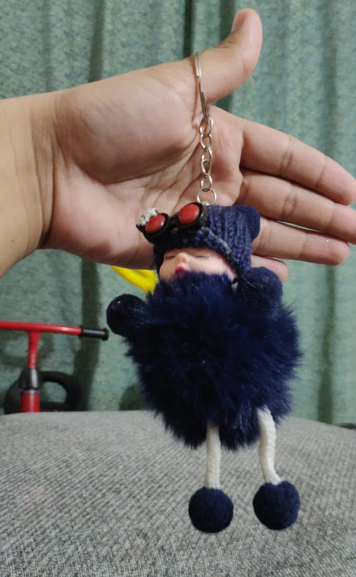 Navy blue sleeping baby doll pom pom keychain held in hand
